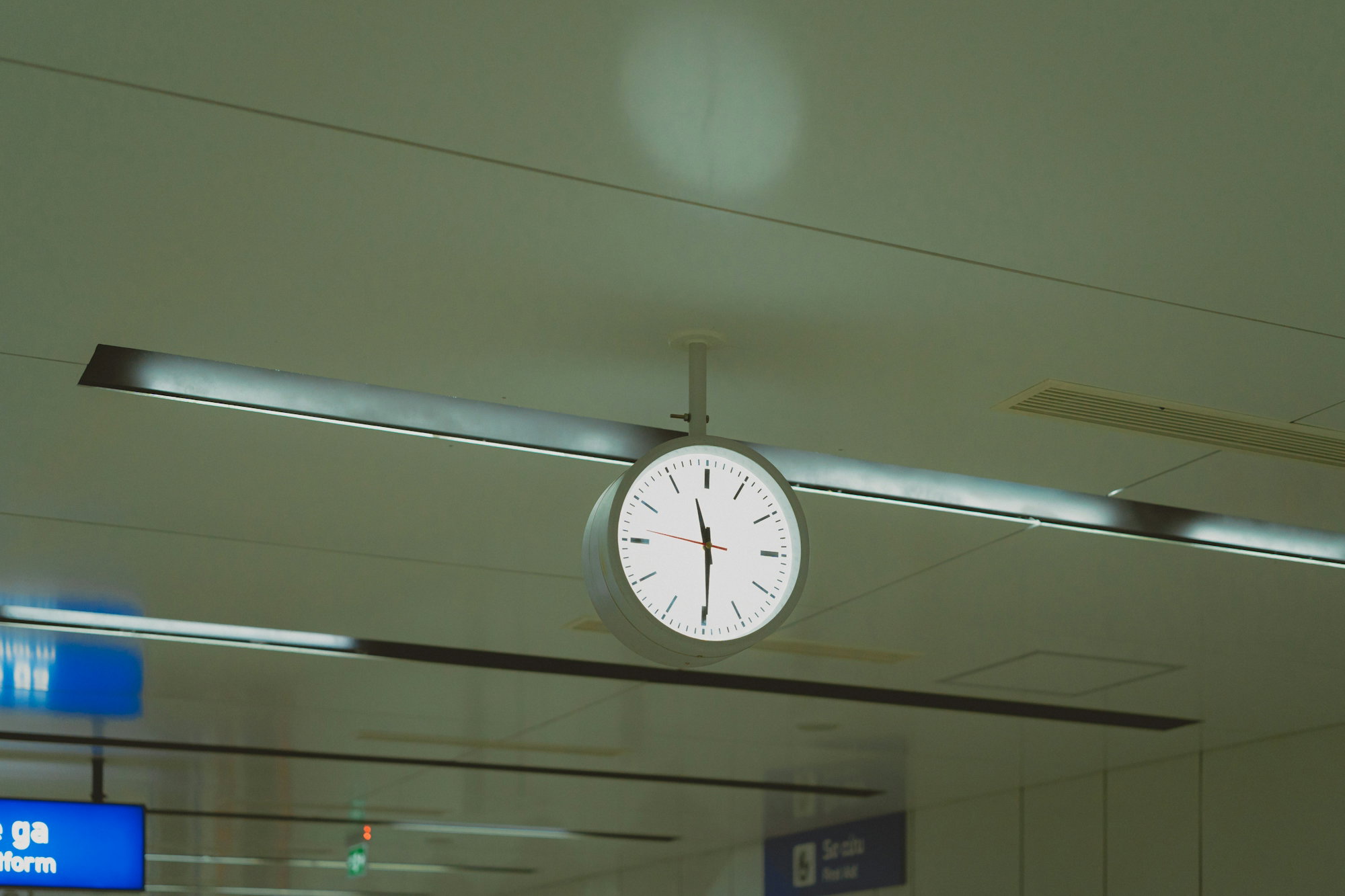 A clock hanging from the ceiling of an airport